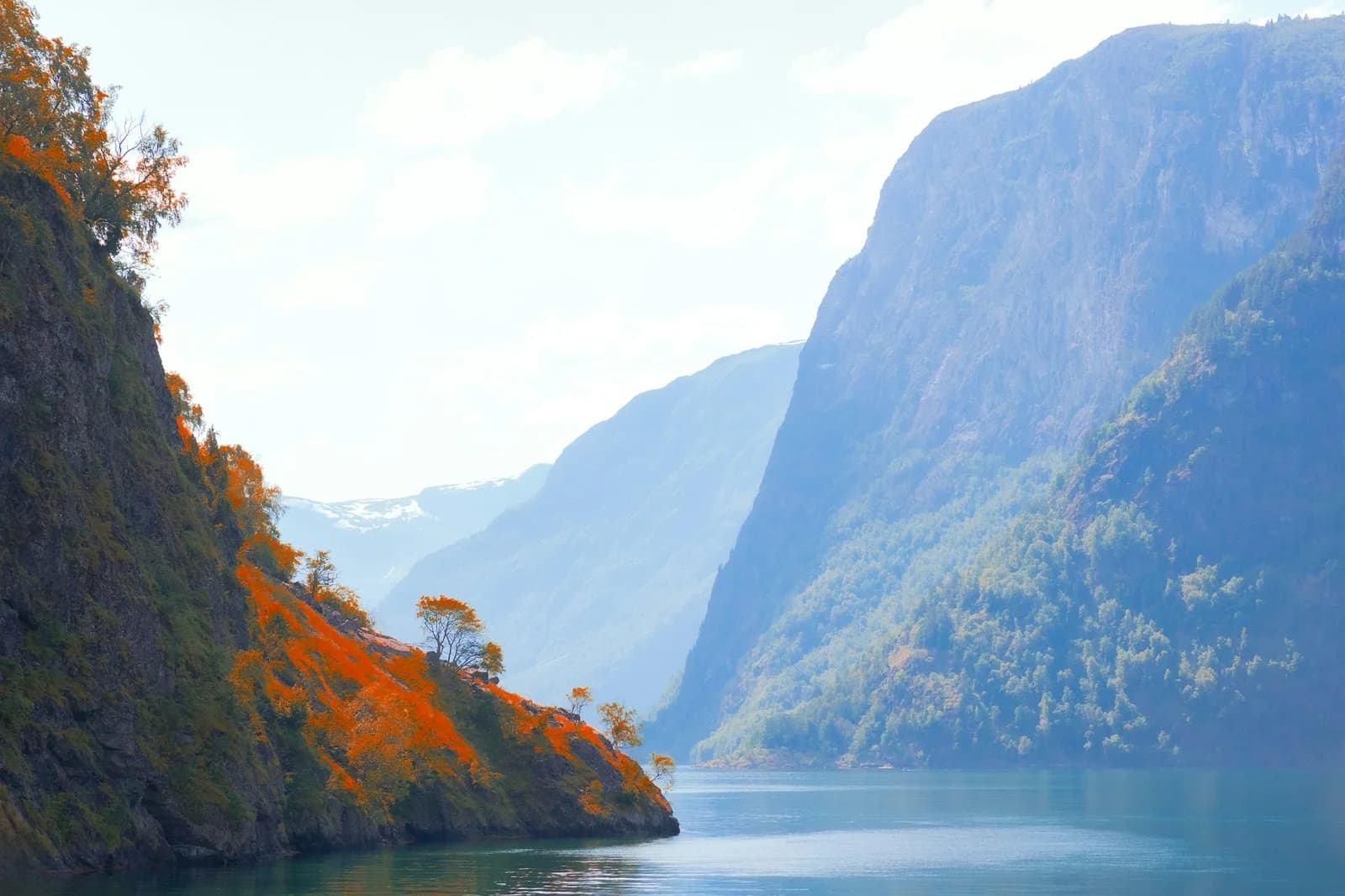 En norsk fjord mellom bratte fjellsider med høstfarger