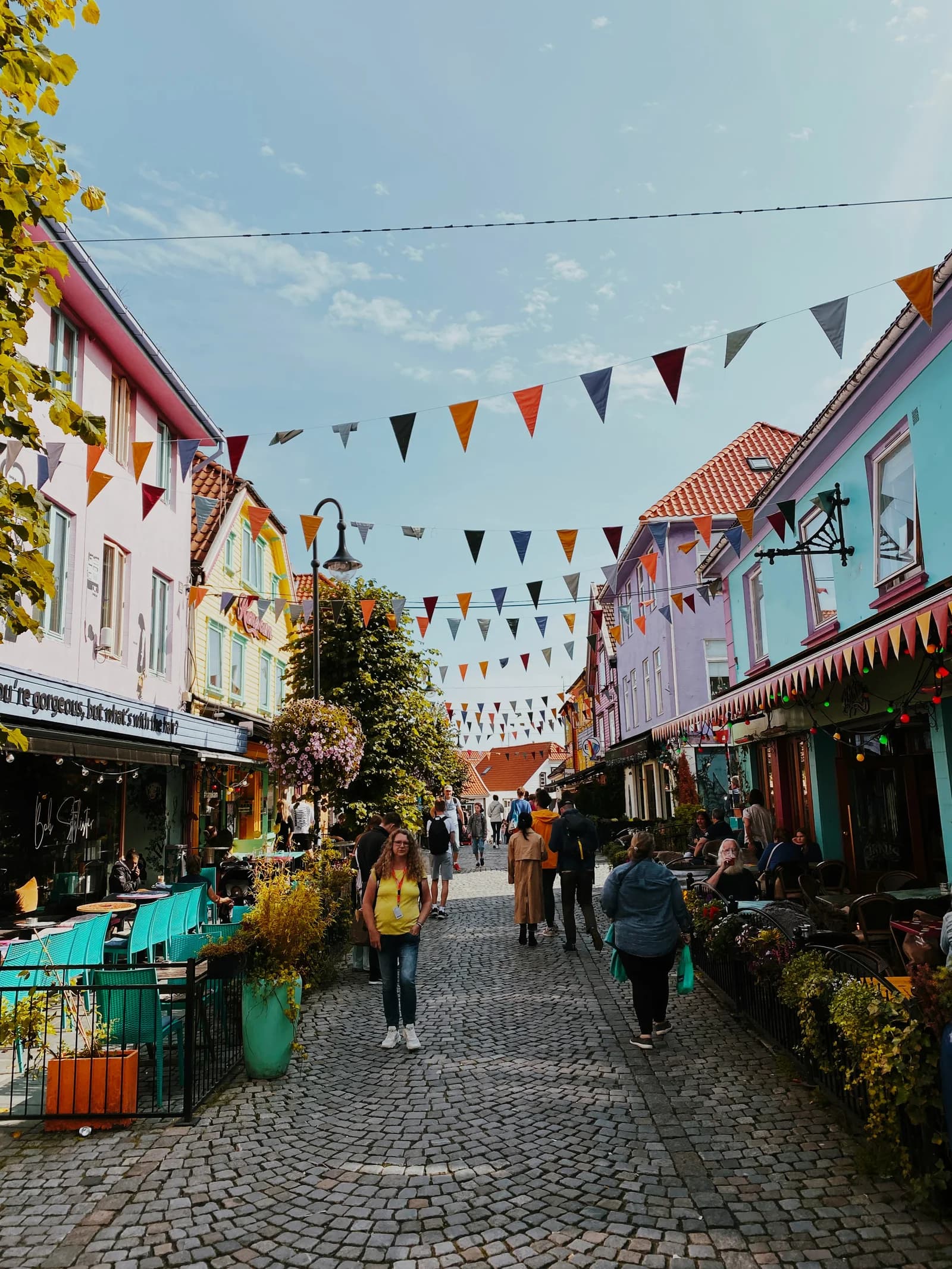 Fargerike butikkfasader, kaféer og vimpler i en gate i Stavanger